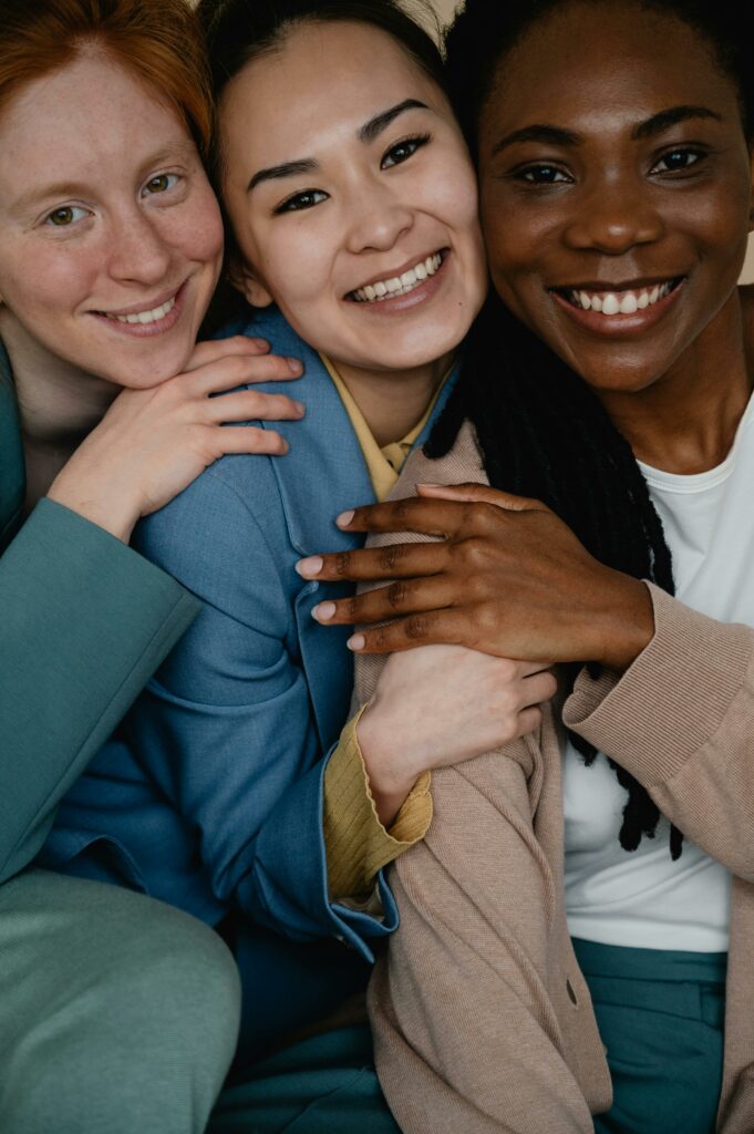 pexels-photo-7506942-7506942 Three diverse women smiling and embracing, symbolizing friendship and unity.